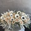 Cream roses and white anemones arranged in a low vase.
