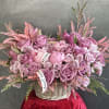 Pink rose arrangement in a wicker basket with ribbon accents