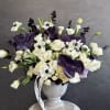 White and purple floral arrangement in a gray urn vase
