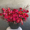 Red and hot pink roses arranged in a black vase with red ribbon