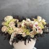 Cream roses and spotted orchids in a round blush vase