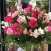 The "Heartfelt Embrace" arrangement combines red and pink roses with mini pink