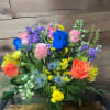 A whimsical mix of multicolored roses, verdant greenery, vivid veronicas, striking delphiniums