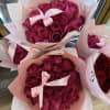 Bouquets of deep pink roses wrapped in pale pink paper with satin bows