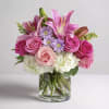Pink lilies, roses, and lavender daisies in a clear glass vase