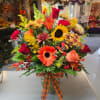 Autumn bouquet with sunflowers, roses, and gerbera daisies in a glass vase