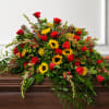 Large arrangement of red roses and yellow sunflowers on a wooden casket
