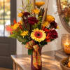 Autumn bouquet of yellow and burgundy flowers in a wrapped vase with plaid ribbon