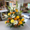 Basket arrangement of yellow roses, white mums, and orange daisies