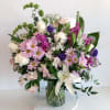 Mixed bouquet of pink, white, and purple flowers in a glass vase