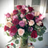 Bouquet of red, pink, and lavender roses in a clear glass vase