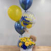 Blue and yellow flower hat box with baby-themed balloons and a teddy bear.