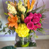 Bouquet of pink roses, orange lilies, and yellow hydrangeas in a glass vase