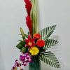 Tropical flower arrangement in a tall green vase with red, yellow, and purple blooms