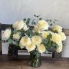 Cream roses arranged in a glass vase with eucalyptus