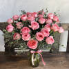 Pink roses arranged in a glass vase with a ribbon