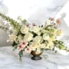 Cream and blush floral arrangement in a gold pedestal vase