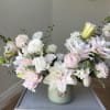 Pastel bouquet of lilies, carnations, and ranunculus in a green vase