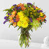 Bright mixed bouquet of yellow, purple, and peach flowers in a glass vase