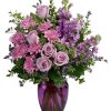 Purple roses and mixed lavender flowers in a purple glass vase