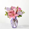 Pink lilies and roses arranged in a purple glass vase