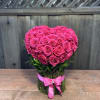 Heart-shaped bouquet of hot pink roses tied with a pink ribbon