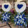 Two large heart-shaped floral tributes with blue roses and white flowers