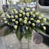 Large floral spray of white roses and blue flowers on a stand