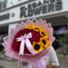 Bouquet of red roses and yellow sunflowers wrapped in pink paper