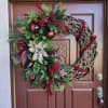 Holiday wreath with evergreen branches, red ribbons, and ornaments on a front door