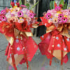 Two bright standing flower arrangements with red and gold wrapping