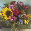 Bouquet of sunflowers, red roses, and pink mixed flowers in a glass vase