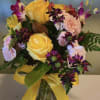 Bouquet of yellow and pink roses in a glass vase with a yellow ribbon