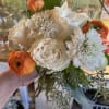 Handheld bouquet of white roses, white blooms, and orange ranunculus