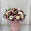 Mixed pink, lavender, and white roses arranged in a pink box