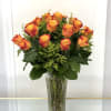 Orange roses arranged in a tall clear glass vase
