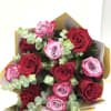Bouquet of red and lavender roses wrapped in gold and white paper