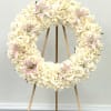 Cream rose wreath with pale pink lilies on a wooden stand