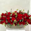 Low arrangement of red roses in a shallow bowl with eucalyptus accents