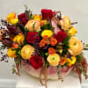 Mixed roses and ranunculus arranged in a pink pumpkin vase
