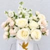 White and blush roses arranged in a white vase with a gold dove emblem
