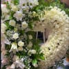 Large white floral wreath with roses and daisies on an easel