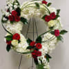 Heart-shaped floral wreath with red roses and white hydrangeas on a stand
