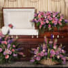Casket surrounded by pink and purple funeral flower arrangements