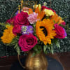 Bright mixed bouquet in a gold pitcher vase with a birthday topper