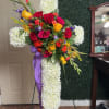 Standing floral cross with red, yellow, and white flowers on an easel