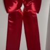 Large red satin bow with long ribbon tails hanging on a wall