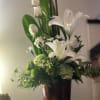 White lilies and roses in a dark vase with green foliage