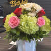 Birthday flower arrangement with roses and hydrangeas in a glass vase
