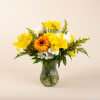 Yellow and white mixed flowers in a clear glass vase